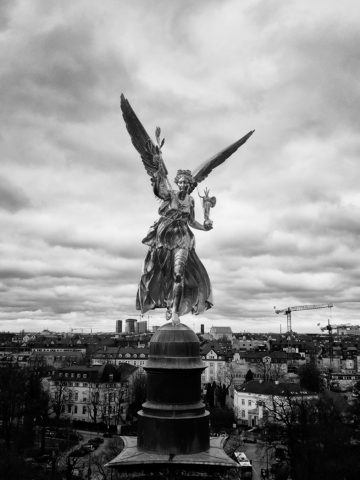 Der Friedensengel vor Münchens Stadtbild in schwarz-weiß. Fotografie von James Murray.