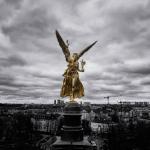 Der Friedensengel in Gold vor Münchens Stadtbild in schwarz-weiß. Fotografie von James Murray.