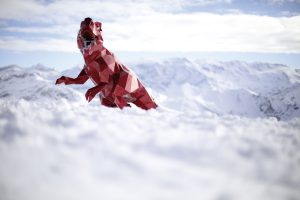 Dino-James_Murray-Bild-artig Roter Spielzeug-Dinosaurier in den französischen Alpen. Fotografie von James Murray.